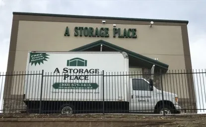 A moving truck in front of a storage place storage facility.