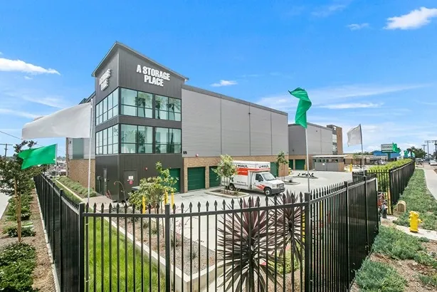 A storage place building with a moving truck and gate.